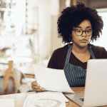 Restaurant owner processing Restaurant Payroll Canada on a laptop
