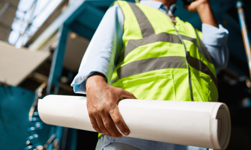 Construction worker holding blueprints, symbolizing T5018 filing requirements for contractors and businesses.